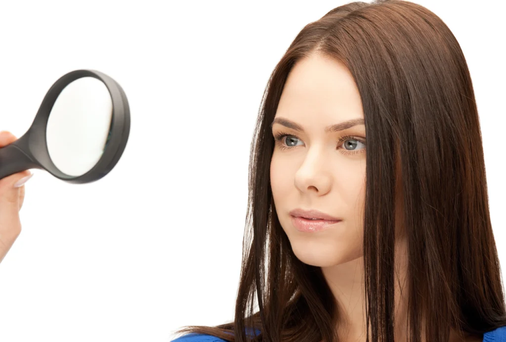 Close-up of a woman looking through a magnifying glass to inspect hair density for a hair transplant in Dubai.