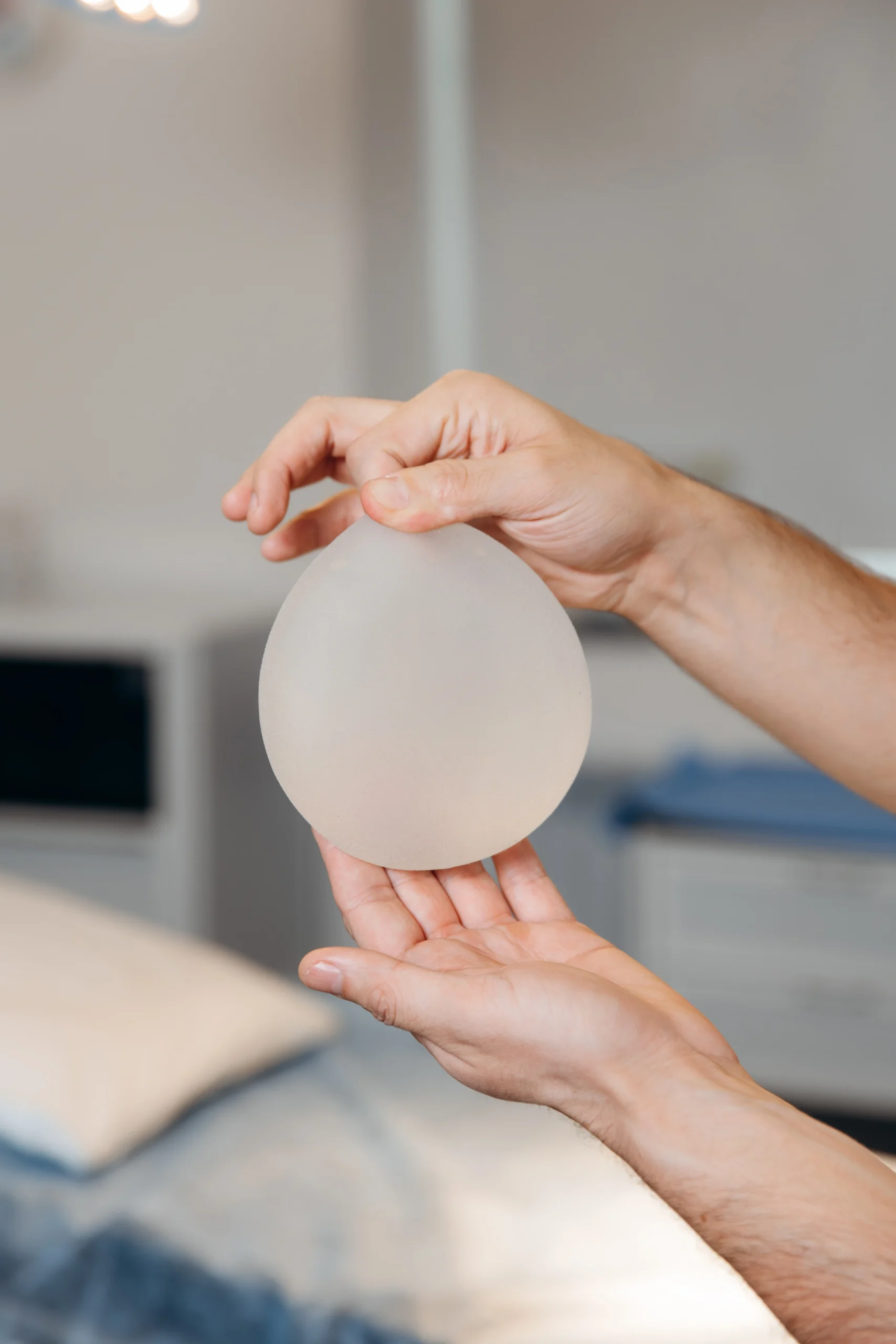 Surgeon holding a round silicone breast implant in Dubai to demonstrate shape and texture.