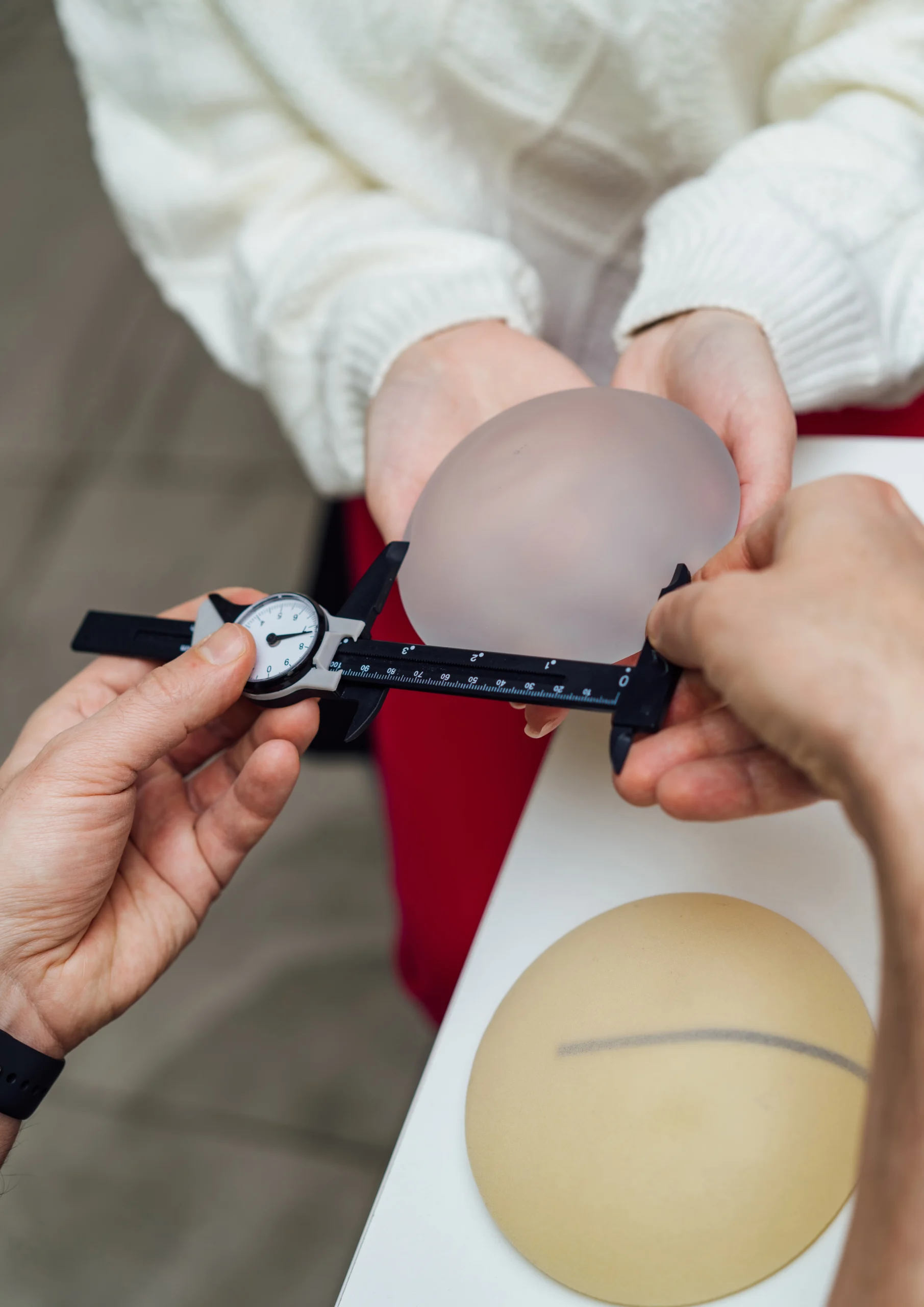 Medical professional using a caliper to measure a silicone breast implant in Dubai for patient sizing.