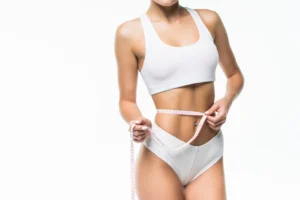 Patient measuring abdominal circumference after surgical liposuction in Dubai.