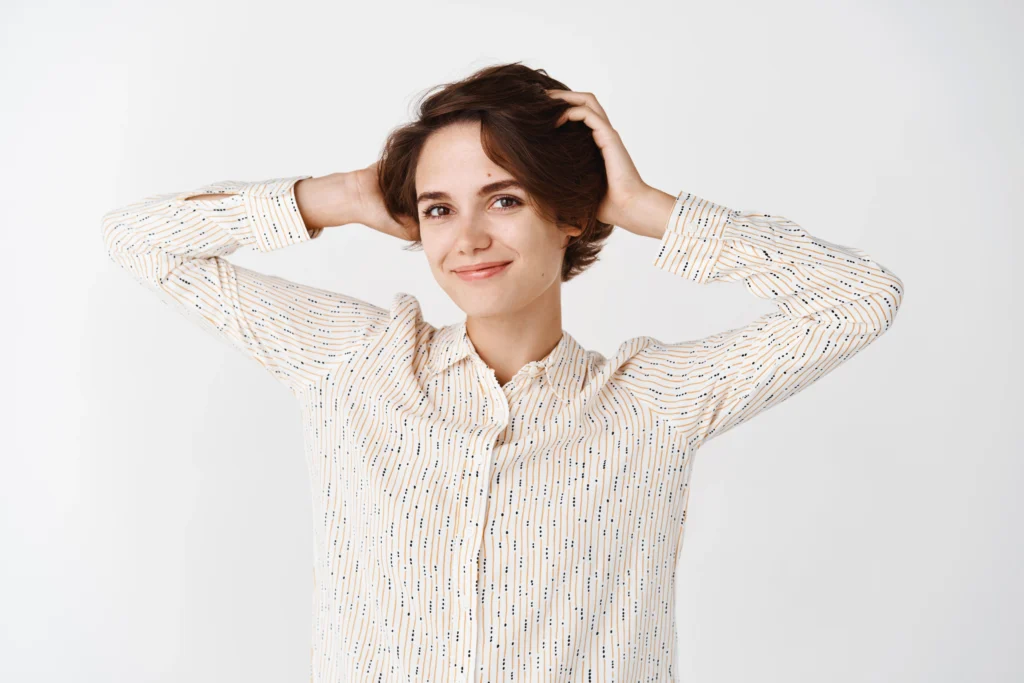A smiling young woman with a healthy, short hairstyle running her hands through her hair after a hair transplant in Dubai.