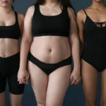 A frontal studio portrait of three women of diverse body types standing side-by-side in white underwear against a light beige background, showcasing varying abdominal profiles to illustrate the combined approach of Liposuction vs Tummy Tuck: Combined Procedures Dubai.