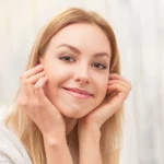 A female patient smiling with restored facial symmetry, firmer cheek contours, and a defined jawline following a natural facelift procedure by Dr. Sanjay Parashar.